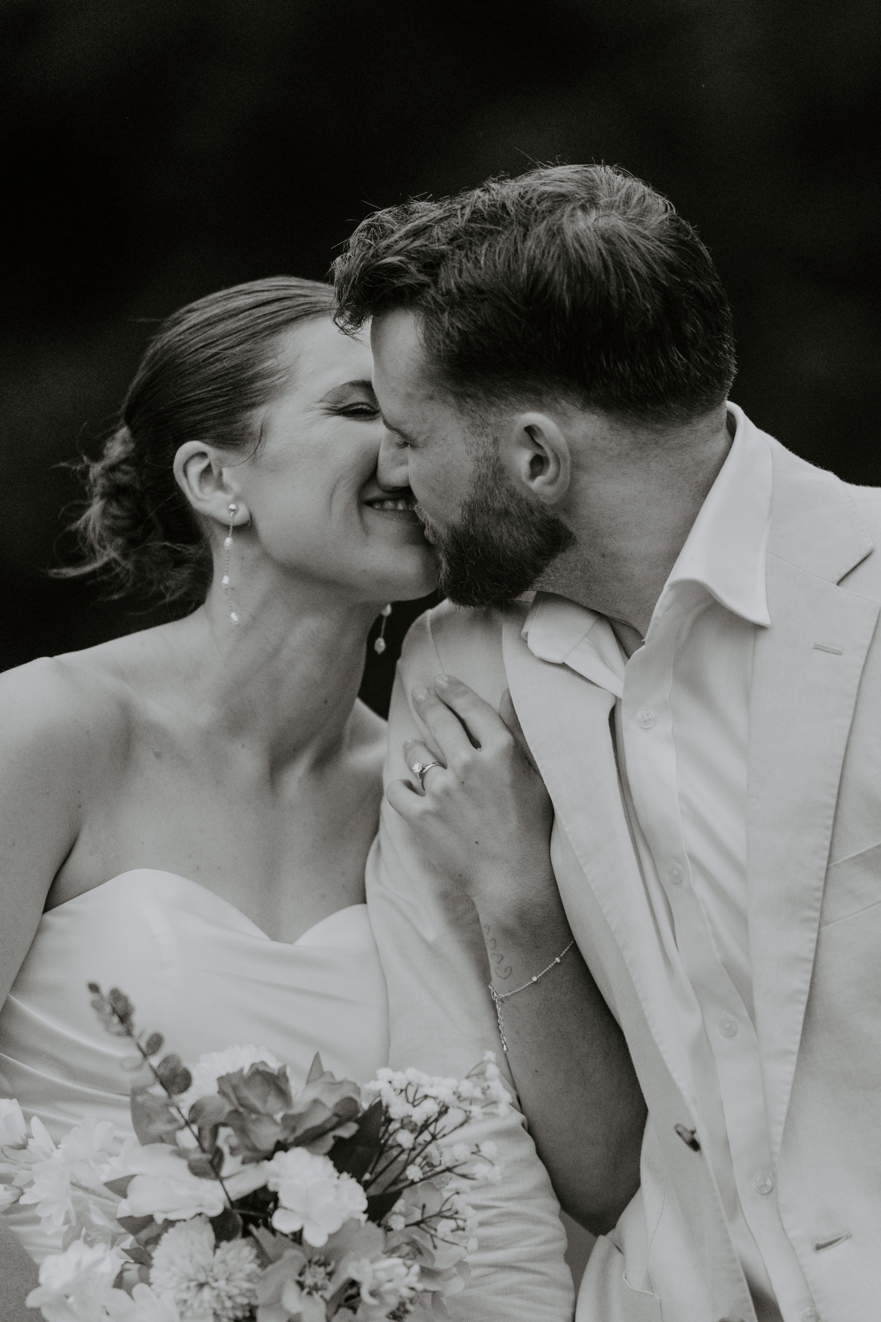 A smiling couple, with the woman laughing and the man smiling in the background.